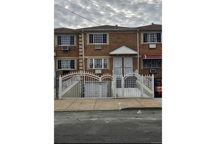Traditional-style house with a gate, a fenced front yard, and brick siding