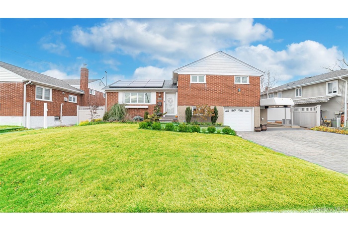 View of front of home with brick siding, solar panels, decorative driveway, and a garage