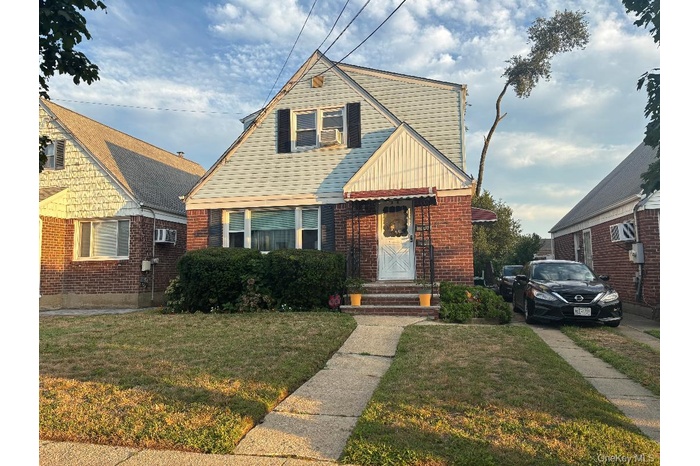 Bungalow with a front yard and brick siding