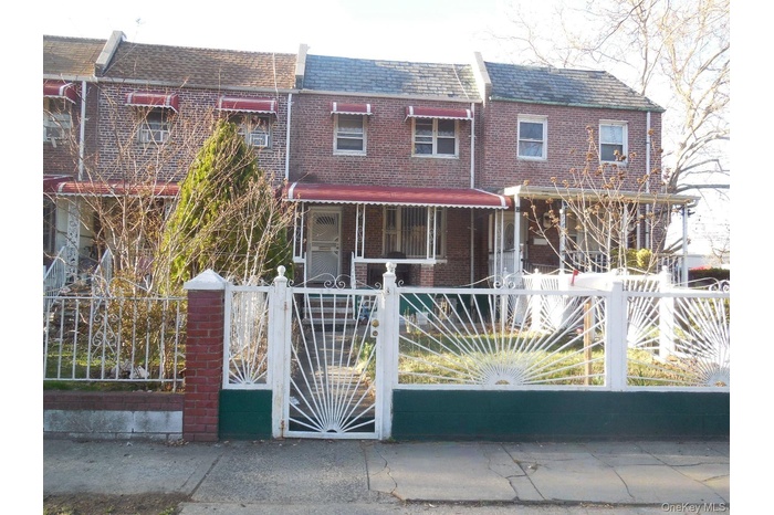 Traditional-style house with a gate, brick siding, and a fenced front yard