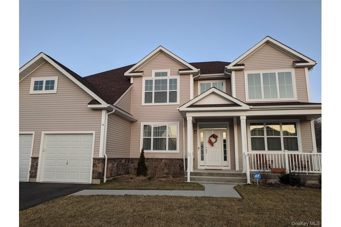 View of front of home featuring a porch, driveway, a shingled roof, an attached garage, and a front lawn