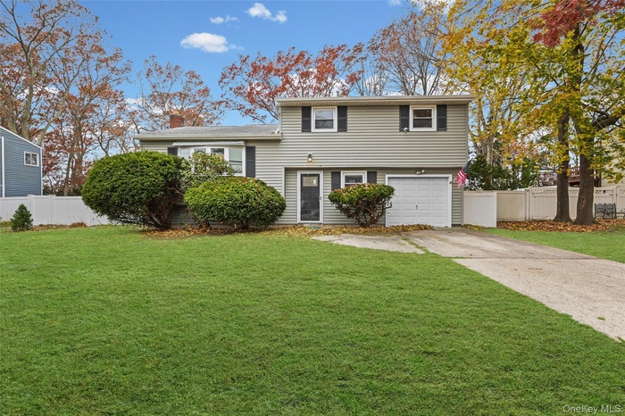 Tri-level home with driveway, an attached garage, and a chimney