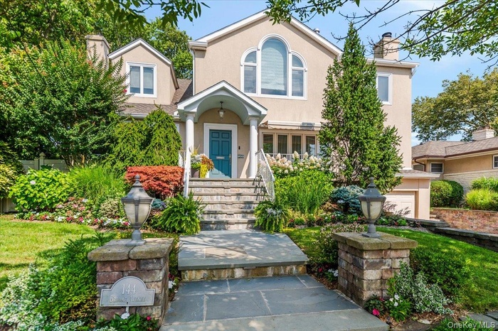 View of front of home with stucco siding, a chimney, and a front lawn