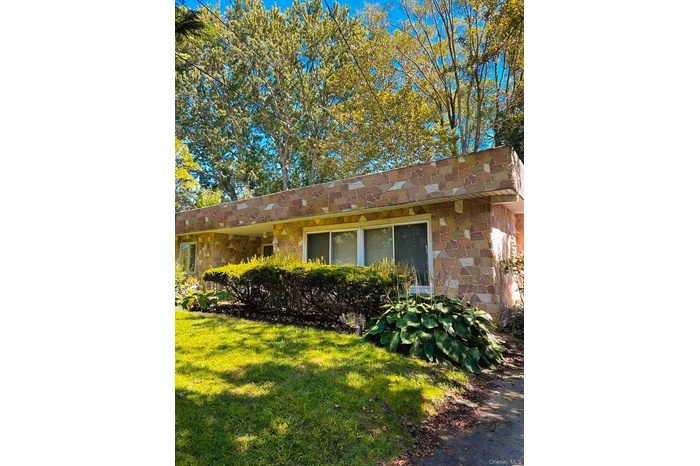 View of property exterior featuring stone siding and a lawn