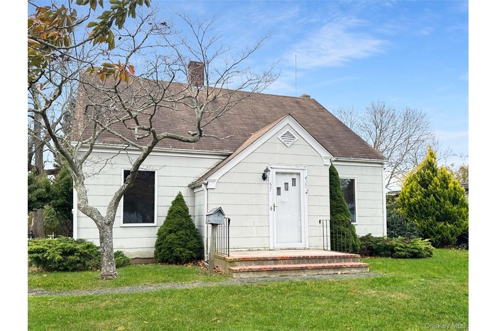 View of front of property featuring a front yard, a chimney, and roof with shingles