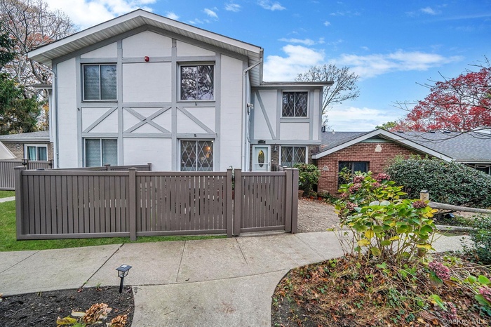 View of front facade with a fenced front yard, stucco siding, a gate, and brick siding