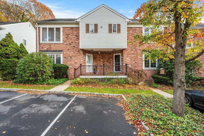View of front facade with uncovered parking and brick siding