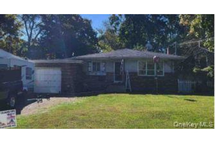 View of front facade with a front lawn, an attached garage, and driveway