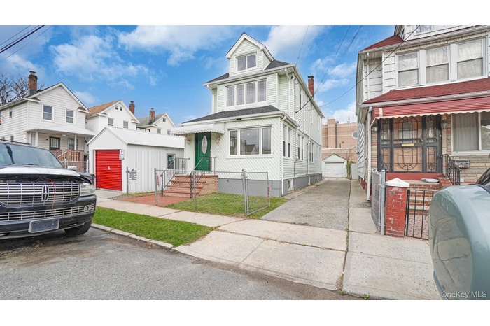 American foursquare style home featuring an outdoor structure, a garage, a residential view, and a gate