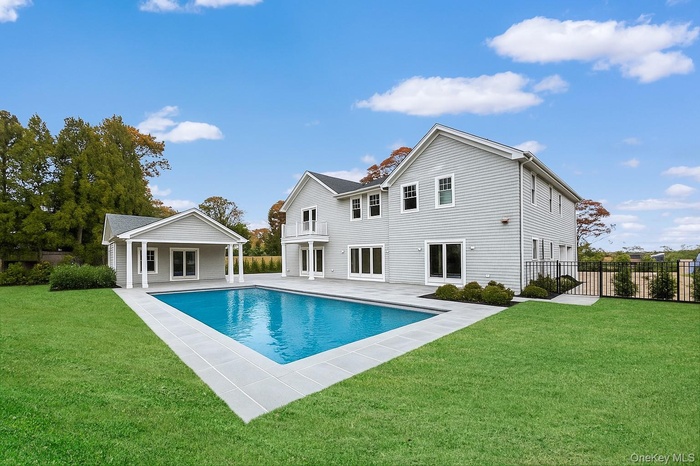 Rear view of property featuring a lawn, a patio, a storage structure, and an outbuilding