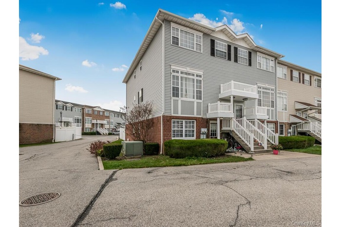 View of front of property with brick siding, stairs, a balcony, and a residential view