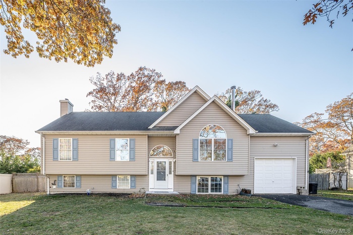 Raised ranch featuring a chimney and driveway