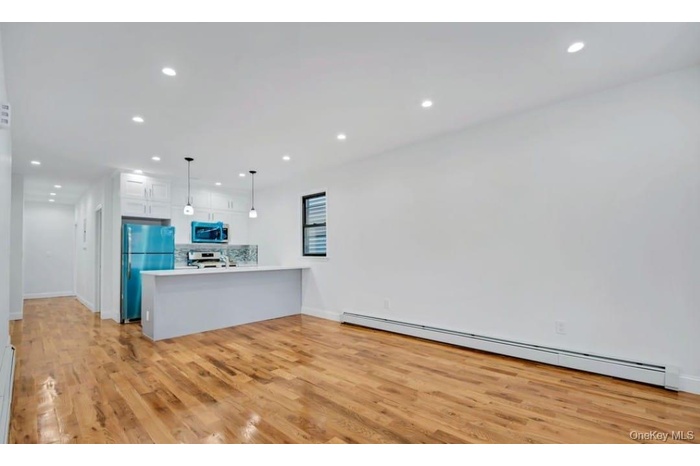 Kitchen featuring a peninsula, a baseboard heating unit, light countertops, decorative light fixtures, and light wood-type flooring