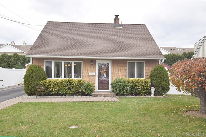 View of front of property with a chimney and a shingled roof