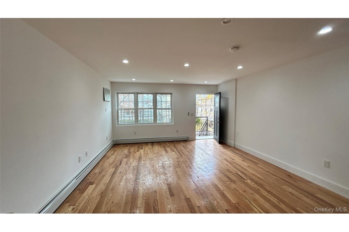Empty room with a baseboard radiator, light wood-style flooring, and recessed lighting