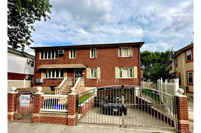 View of front facade with a gate, a fenced front yard, and brick siding