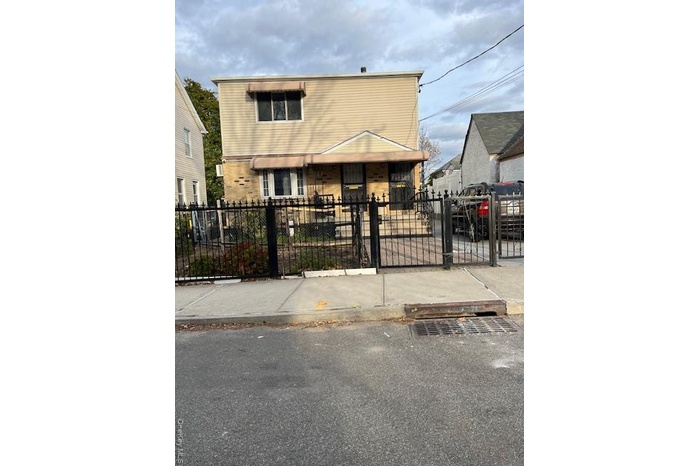 Colonial-style house featuring a gate, a fenced front yard, and brick siding