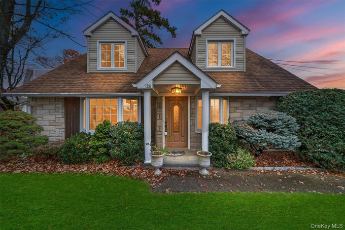 View of front facade featuring stone siding, a front lawn, and a shingled roof