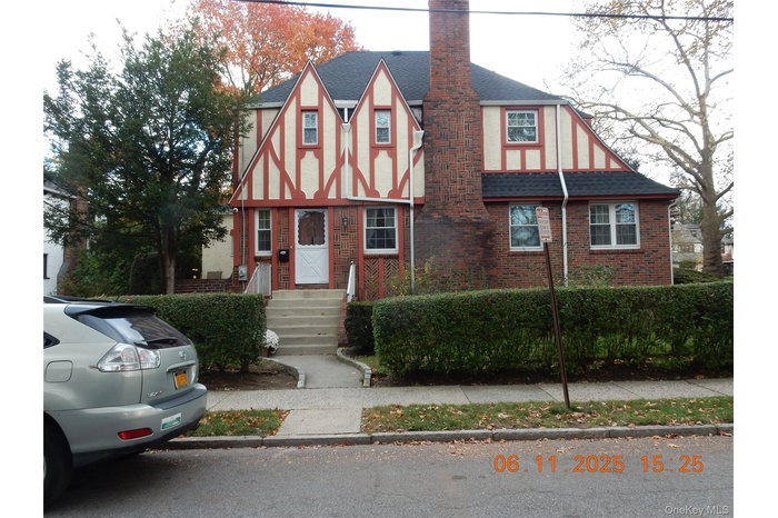 Tudor home with a shingled roof, brick siding, and a chimney