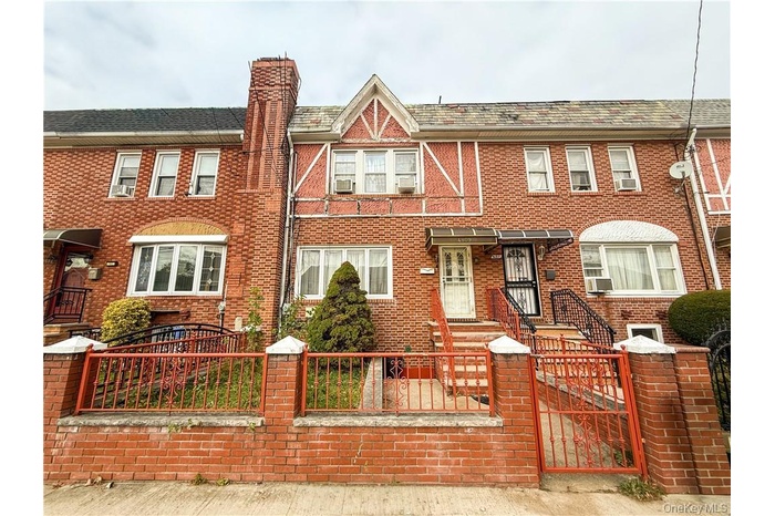 View of front of home featuring a gate, a fenced front yard, a chimney, and brick siding