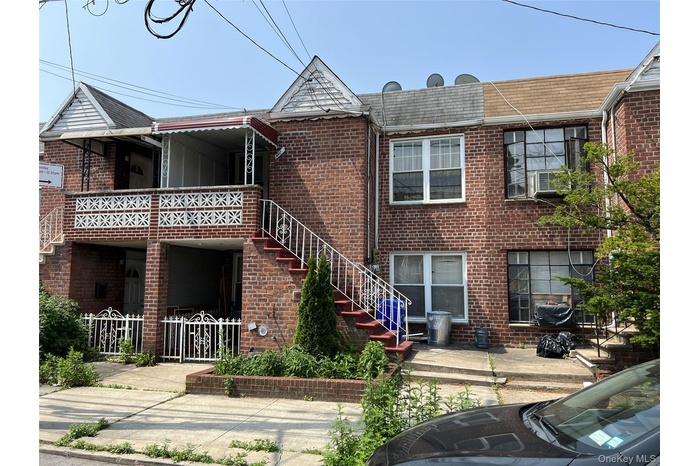 View of front of home featuring brick siding, stairway, and a shingled roof