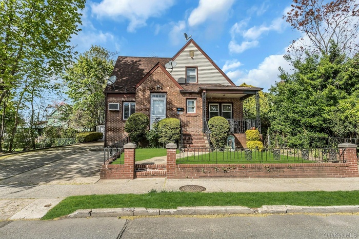 View of front facade with brick siding, a porch, a shingled roof, and driveway