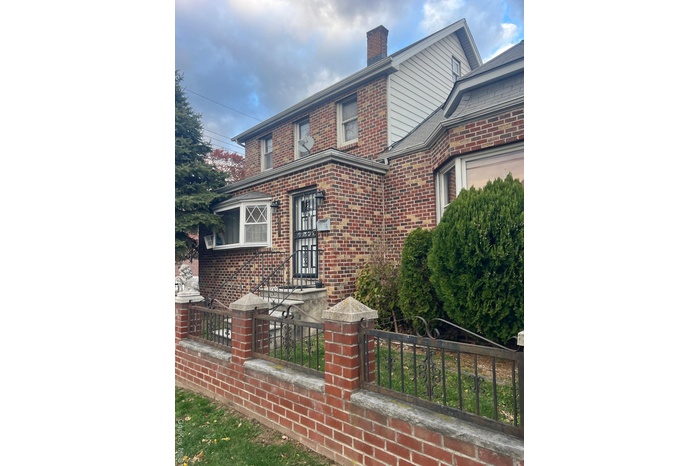 View of front of property featuring brick siding and a chimney
