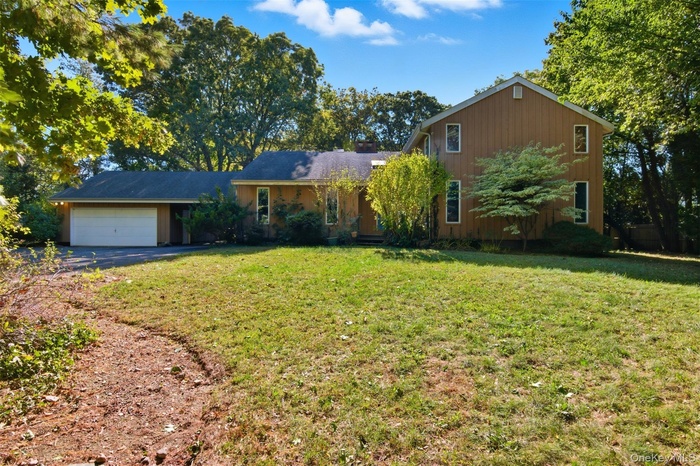 View of front of house featuring a front lawn, an attached garage, and driveway