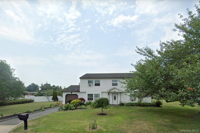 View of front of home with a front lawn, a garage, and driveway