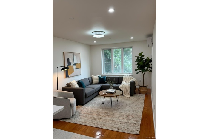 Living area with wood finished floors, a wall mounted AC, and recessed lighting