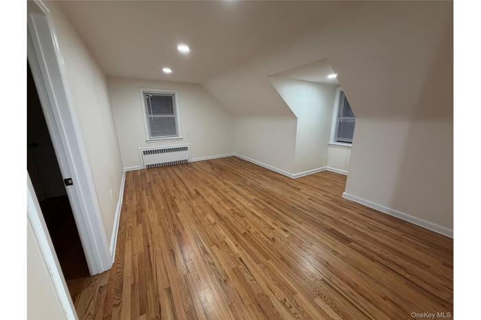 Additional living space with light wood-style flooring, radiator, recessed lighting, and lofted ceiling