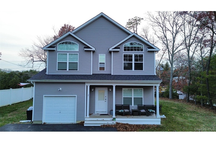 Traditional-style house featuring covered porch, an attached garage, driveway, a front lawn, and a shingled roof