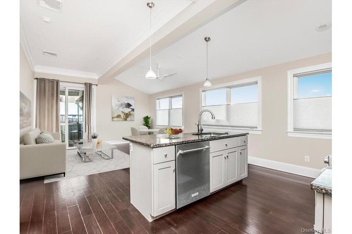 Kitchen with decorative light fixtures, dark stone counters, open floor plan, and healthy amount of natural light