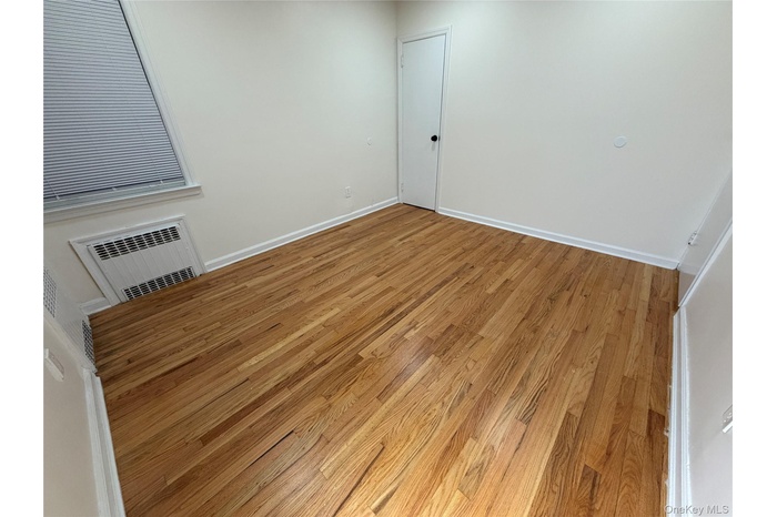 Spare room with light wood-type flooring and a wall unit AC