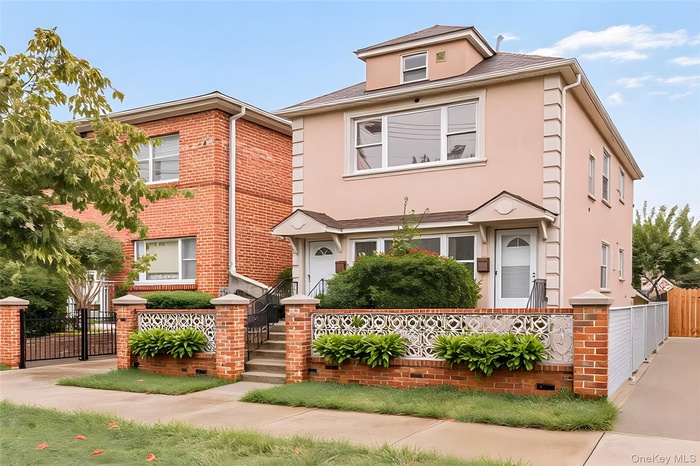 View of front of house featuring a fenced front yard, brick siding, a gate, and stucco siding