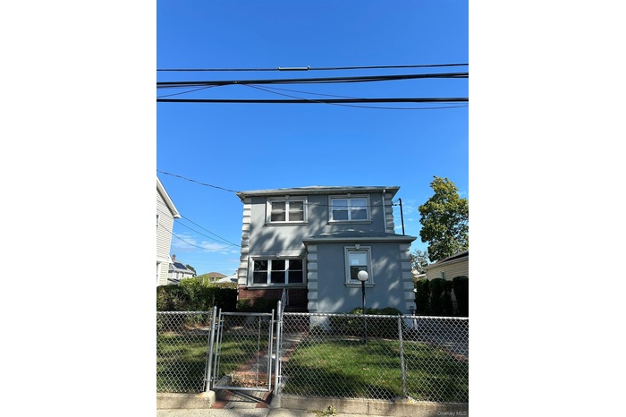 View of front facade featuring a gate, a fenced front yard, and brick siding
