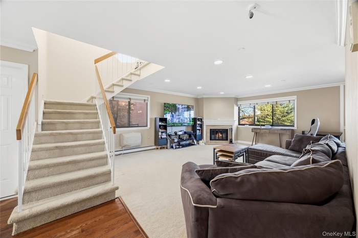 Living room with crown molding, stairs, fireplace, wood finished floors/carpet, and recessed lighting