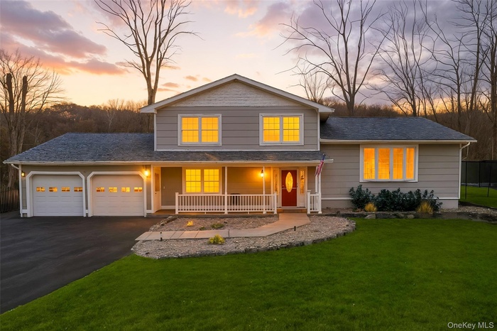 Split level home with a porch, a garage, asphalt driveway, and a yard