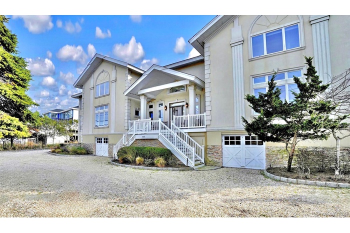 View of front of property featuring an 2 attached garages, stone siding, stairway, stucco siding, and driveway for 6 cars.