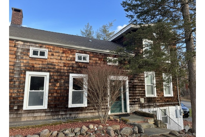 View of home's exterior featuring a shingled roof and a chimney