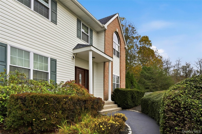 View of exterior entry with brick siding and roof with shingles