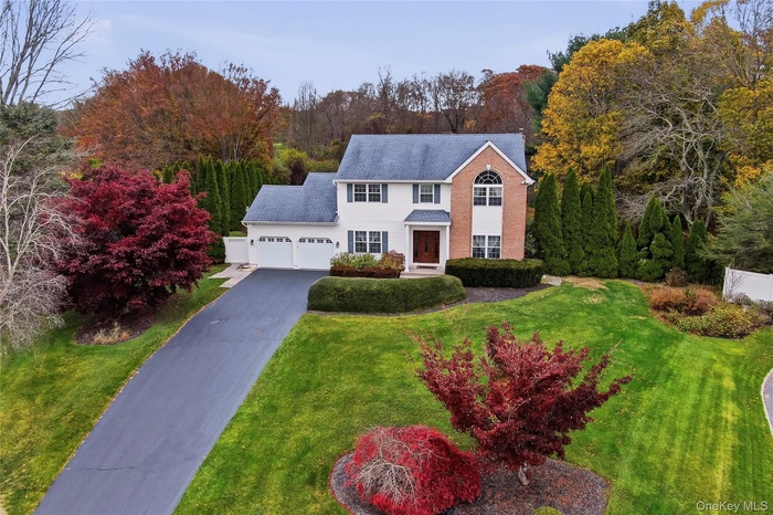 View of front facade featuring driveway, an attached garage, and a front yard