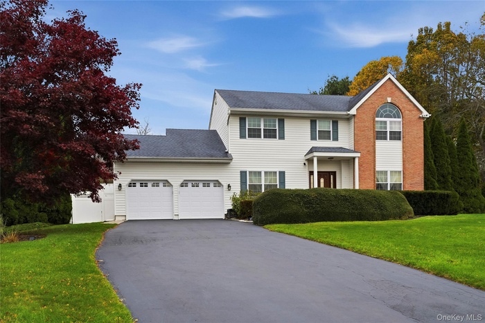 View of front facade with a front lawn, asphalt driveway, a shingled roof, and a garage