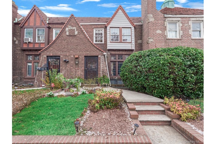 Tudor-style house with a front yard, brick siding, and a chimney