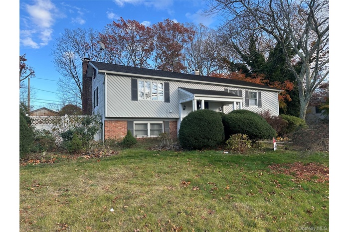 Split foyer home with a chimney, a front yard, and brick siding