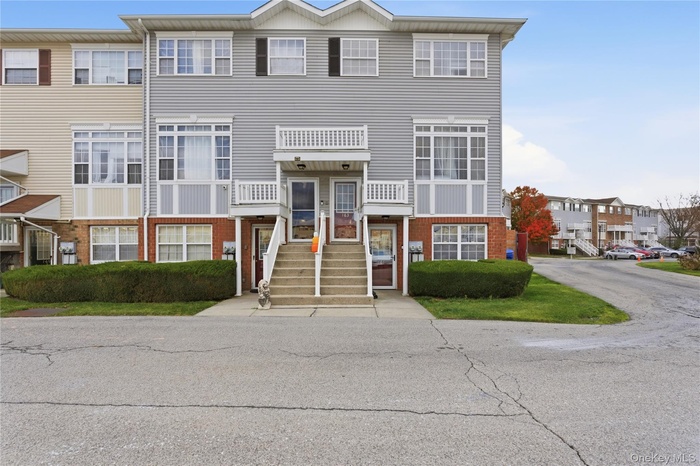 View of front of home featuring brick siding, a balcony, and a residential view
