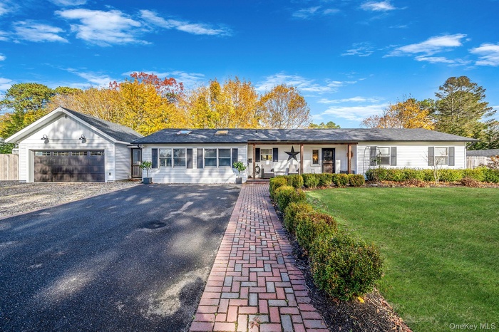 Ranch-style house featuring a front yard, covered porch, and a garage