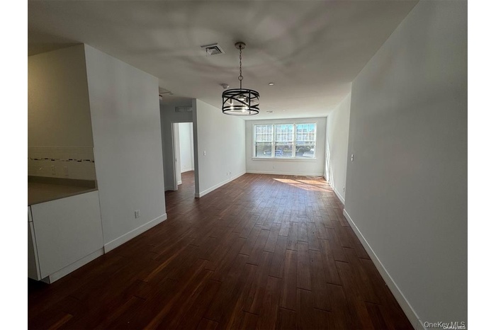 Unfurnished dining area with dark wood-style flooring and a chandelier