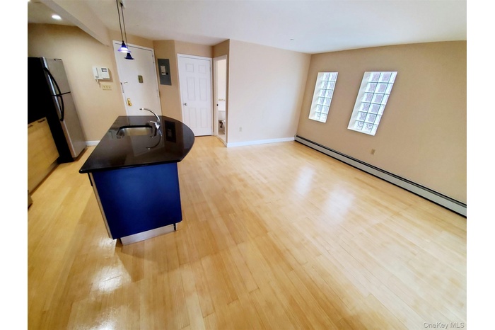 Kitchen featuring dark countertops, freestanding refrigerator, light wood-style flooring, and a baseboard heating unit