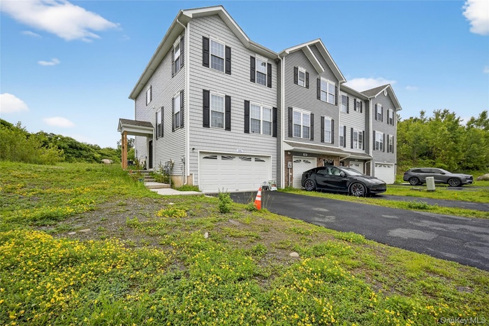 View of property exterior featuring a garage and driveway